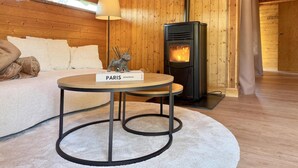 A cozy room with a sofa, a table with a book, a lamp, and a wood-burning stove. - Peace, Comfort & Nature at This Home (Durbuy)