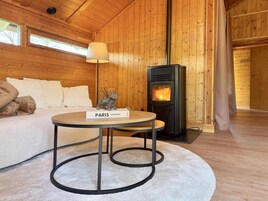 Um quarto aconchegante com sofá, uma mesa com um livro, uma luminária e uma lareira a lenha.