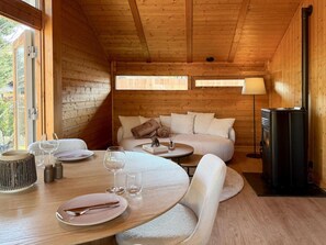 A cozy cabin interior with a dining area, sofa, and fireplace. - Peace, Comfort & Nature at This Home (Durbuy)