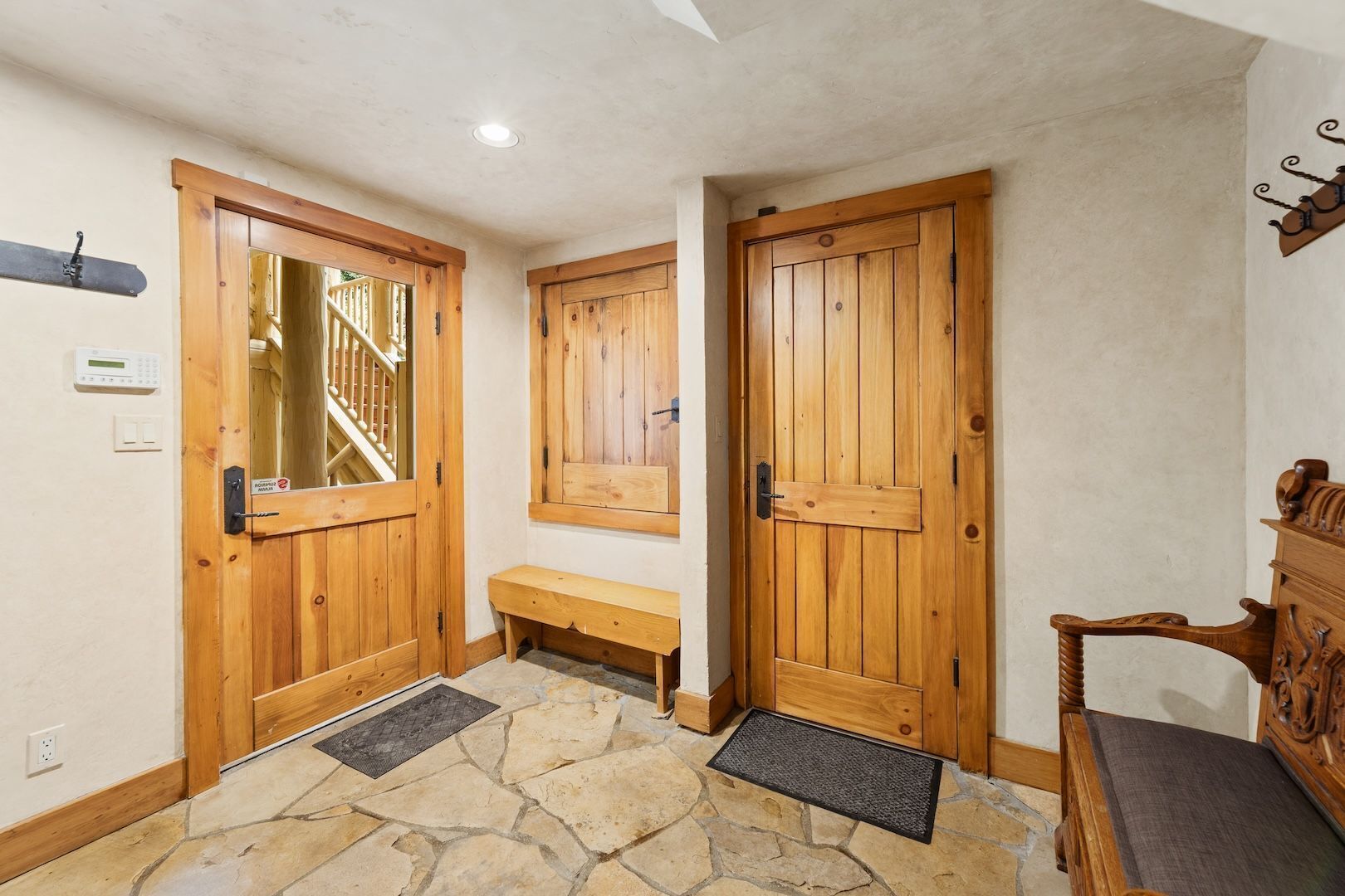 A wooden interior with a stone floor, a bench, and a wooden chair.