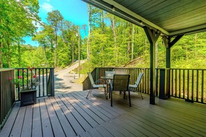 Eine Holterrasse mit Stühlen und Tisch, mit Blick auf ein bewaldetes Gebiet.