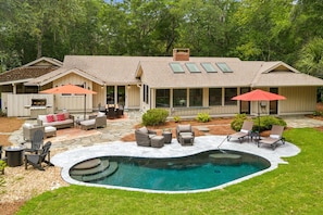 Ein Haus mit Garten, Pool, Gartenmöbeln und einer überdachten Terrasse.