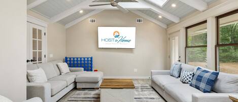 A spacious living room with a high ceiling, a ceiling fan, and a large window providing a view of the outdoors.