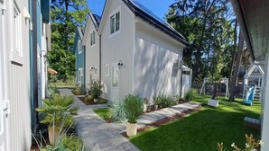A residential property with a paved pathway leading to a house, surrounded by greenery and a play area. - Comfortable Houses With Terraces (Rewal)