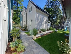 A residential property with a paved pathway leading to a house, surrounded by greenery and a play area. - Comfortable Houses With Terraces (Rewal)