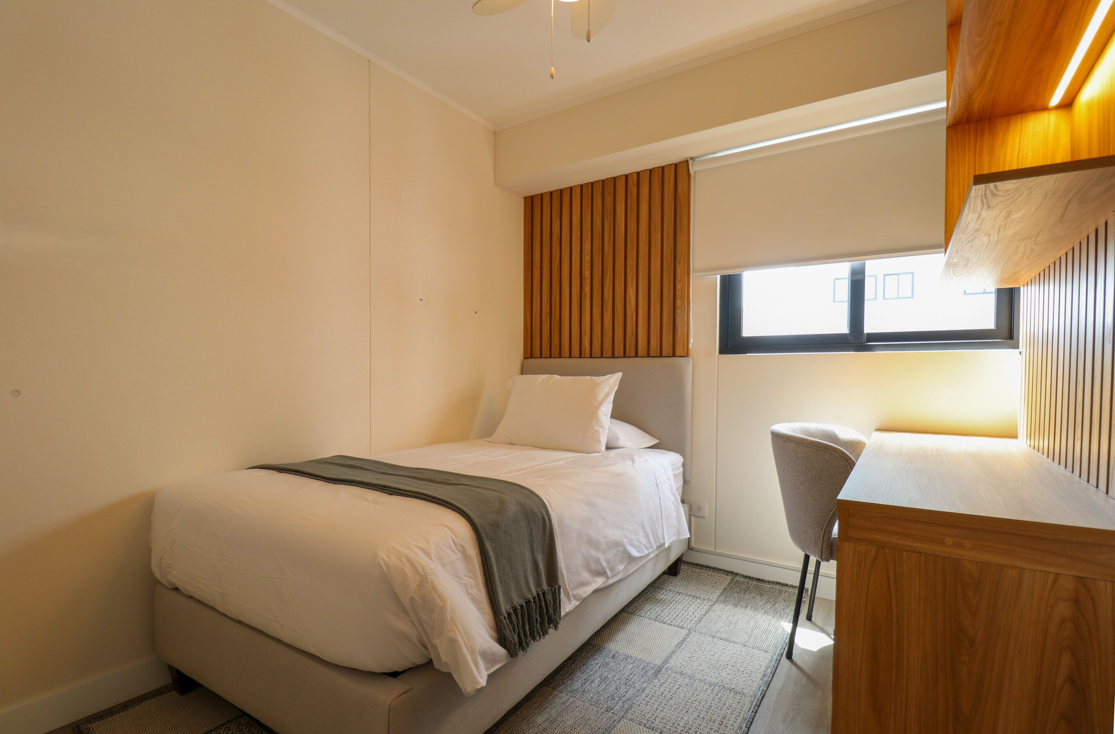 Un dormitorio con cama, escritorio y silla.