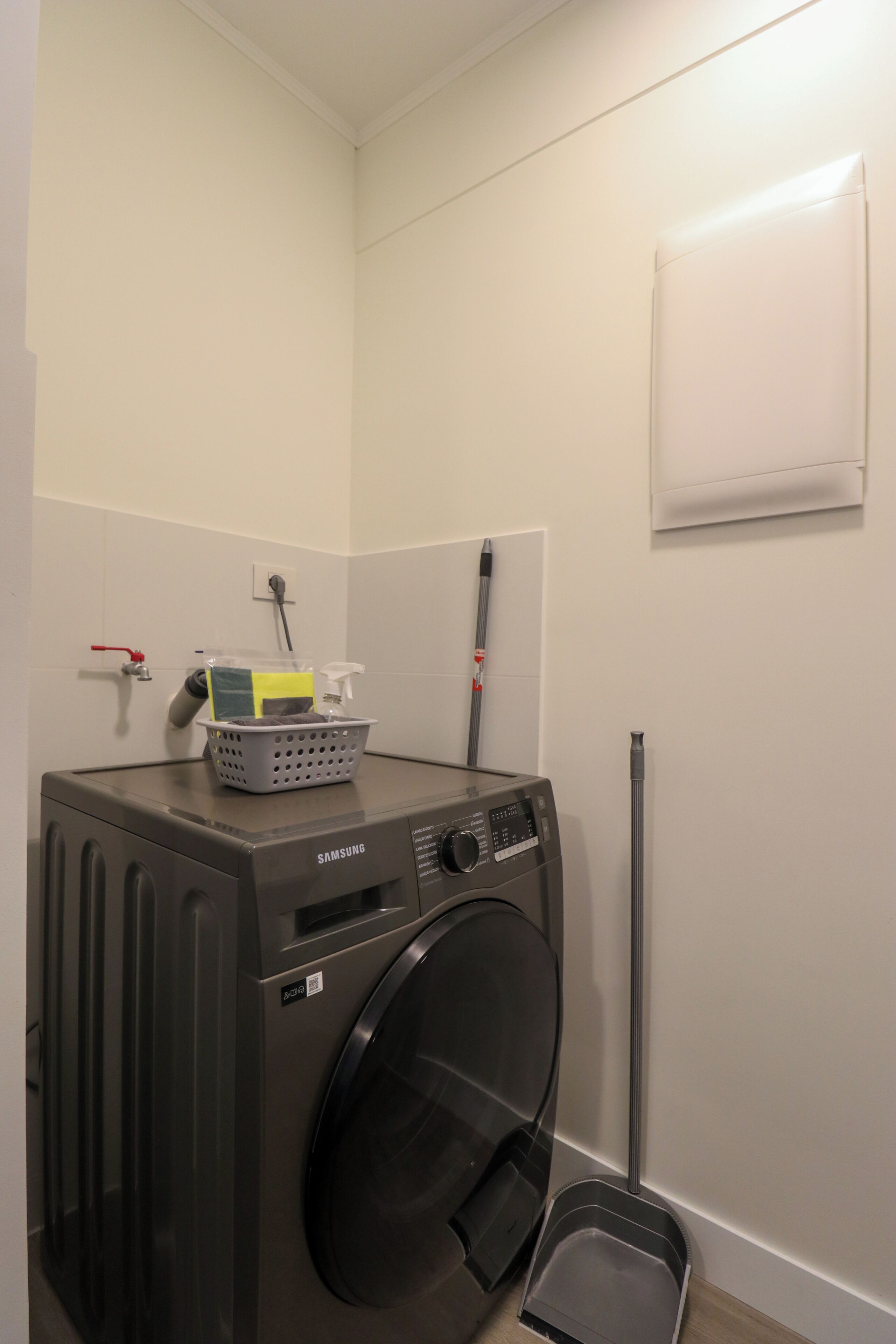 Een wasserette met een wasmachine, een mand en een dweil.