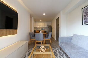 Una sala de estar moderna con un sofá, una mesa de centro y un televisor montado en la pared.