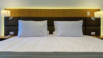 A hotel room with a large bed, two bedside lamps, and a wooden headboard.