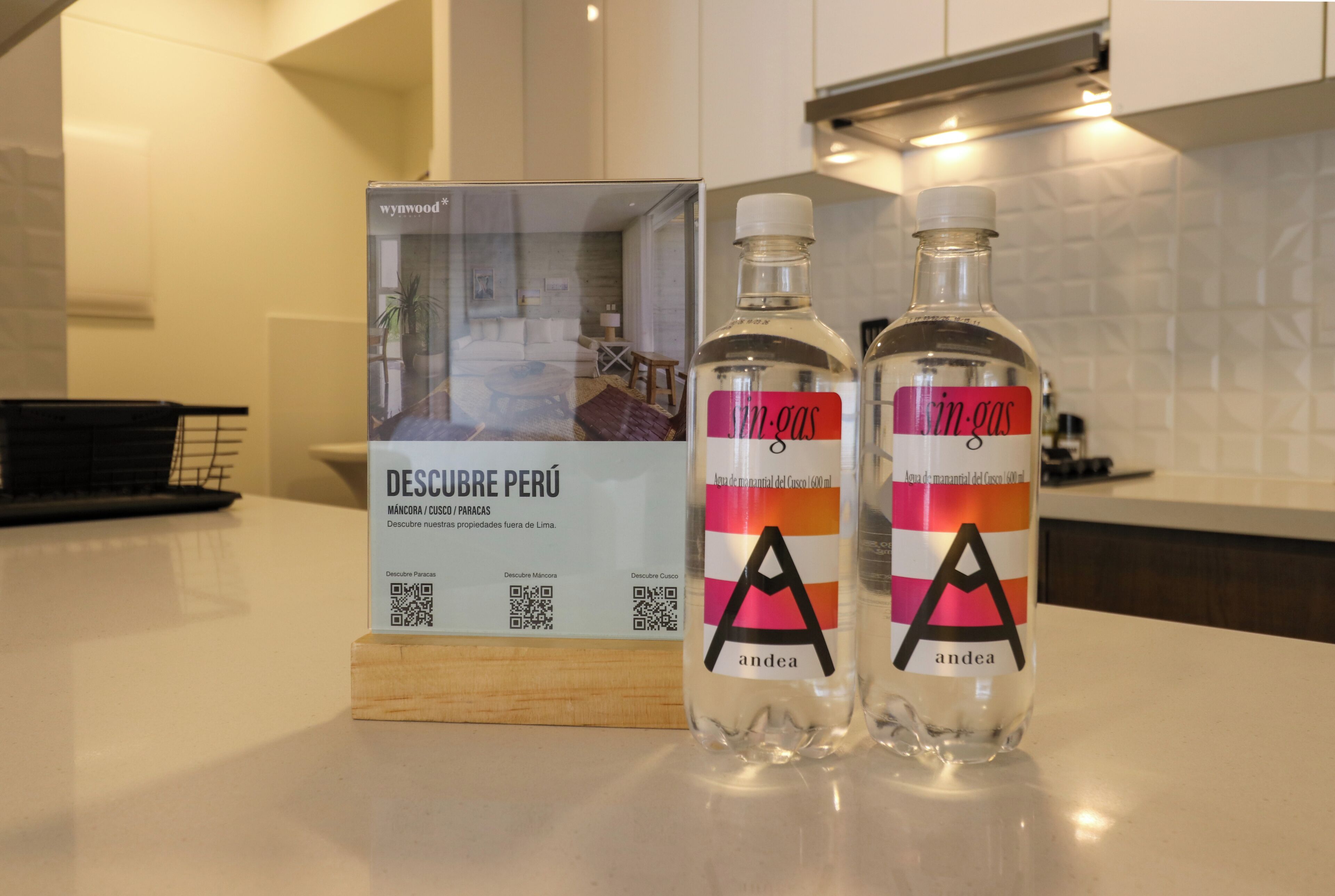 Two bottles of 'sin-gas' water with a wooden stand and a QR code stand with a QR code and text.