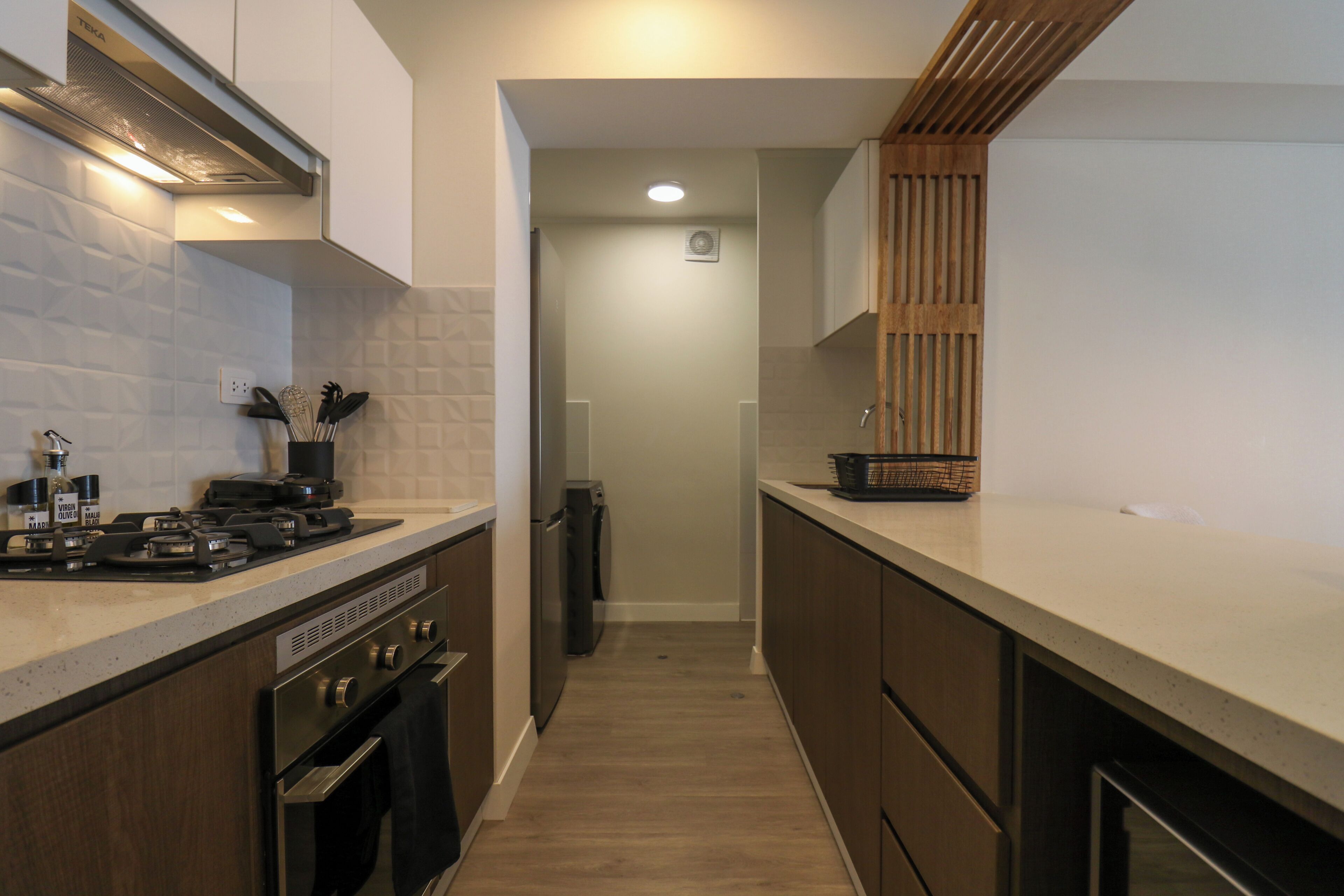 A narrow kitchen with a stove, oven, and dishwasher.