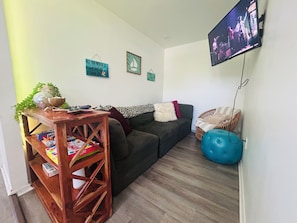 Una sala de estar con un sofá, un televisor, una mesa de madera y una pelota de ejercicio azul.
