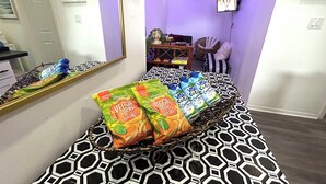Quarto com sofá estampado, televisão fixada na parede e um espelho refletindo parte do ambiente.