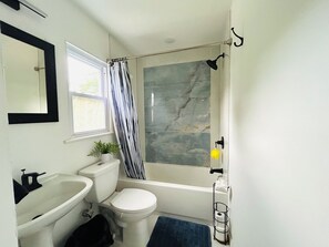 Un baño con inodoro, lavamanos, ducha y espejo.