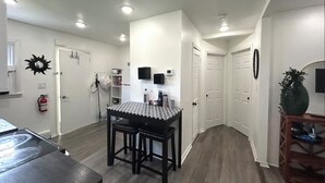 Cozinha compacta com paredes brancas, bancada preta e teto com iluminação embutida.