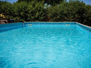 A rectangular swimming pool with clear blue water, surrounded by lush green trees. - Country Holiday Home With Shared Pool (Someren)