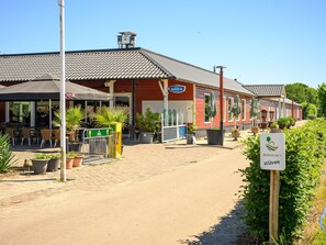 A Bavarian-style building with outdoor seating, a sign reading 'Bavaria,' and a welcome sign. - Country Holiday Home With Shared Pool (Someren)