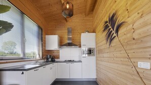 Una cocina moderna con armarios blancos, una campana extractora de acero inoxidable, un microondas y una estufa a gas.