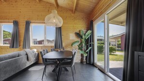 Un interior de madera con una mesa de comedor, sillas, un sofá y un ventanal grande.