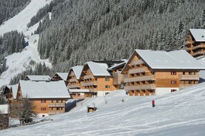 Une rangée de bâtiments de style chalet en bois, dotés de balcons, se dressant sur fond de montagnes enneigées.