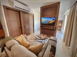 Un salon comprenant un canapé, une table basse et un téléviseur à écran plat fixé sur un mur recouvert de panneaux en bois.
