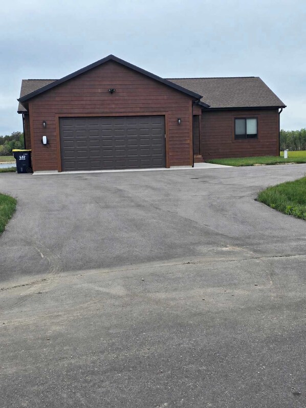 A single-story building with a large garage door, a small attached structure with a window, and a paved driveway. - Sunset Lake |Arcade | Inflatables |Kayak | hot tub (New Lisbon)