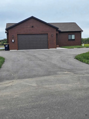 A single-story building with a large garage door, a small attached structure with a window, and a paved driveway.