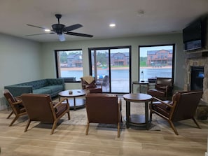 A living room with a green sofa, brown chairs, a small table, and a fireplace.