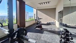 Un gimnasio con equipo de ejercicio, una cinta de correr y vistas a la ciudad.