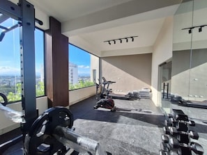 Ein Fitnessraum mit Trainingsgeräten, einem Laufband und Blick auf die Stadt.