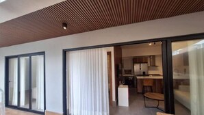 Un interior moderno con cocina, comedor y un gran ventanal corredera que da a un espacio exterior.