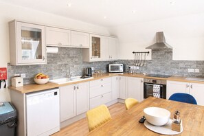 Una cocina moderna con armarios blancos, encimera de madera, microondas integrado y estufa.