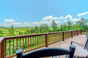 Eine Holzterrasse mit Blick auf eine grüne Landschaft und Bäume.