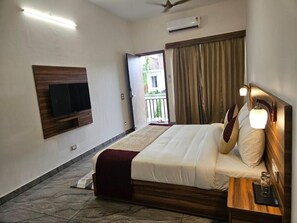 Habitación de hotel con cama, mesita de noche, televisión montada en la pared y vistas al exterior.