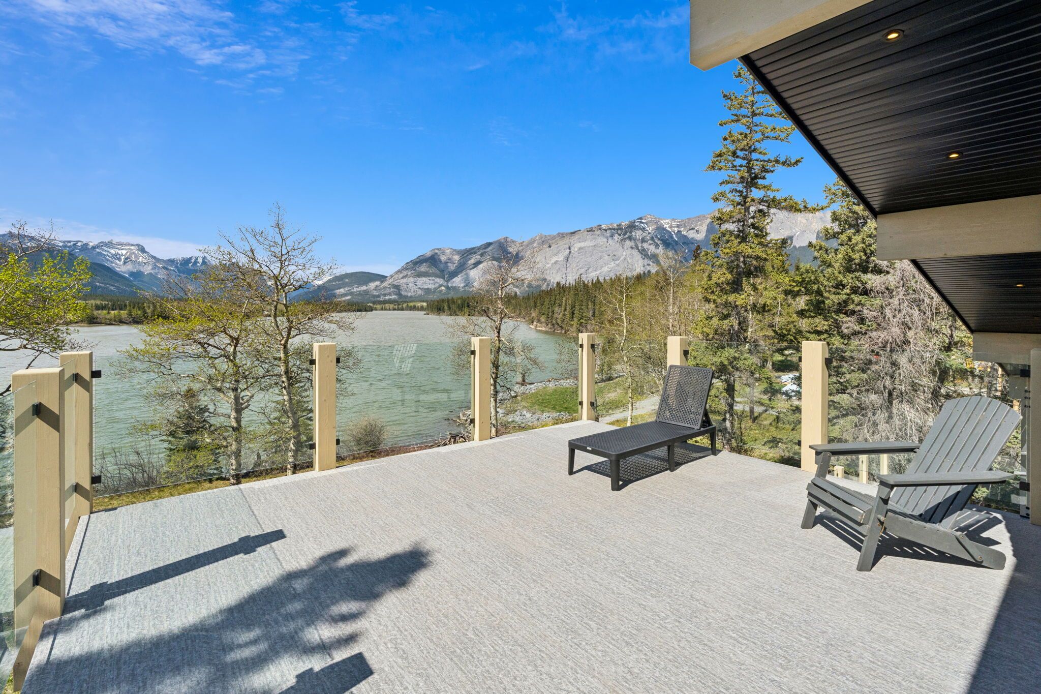 A deck with outdoor seating, overlooking a lake and mountains.