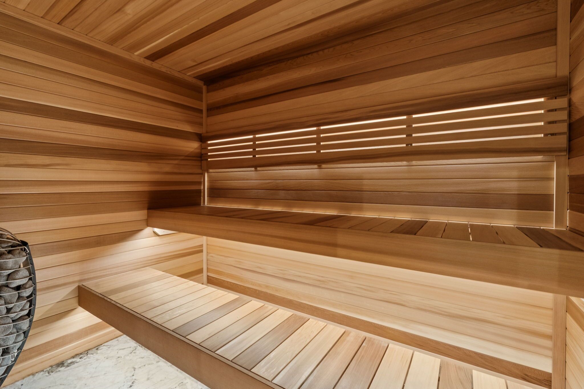 A sauna with wooden benches and slatted ceiling panels.