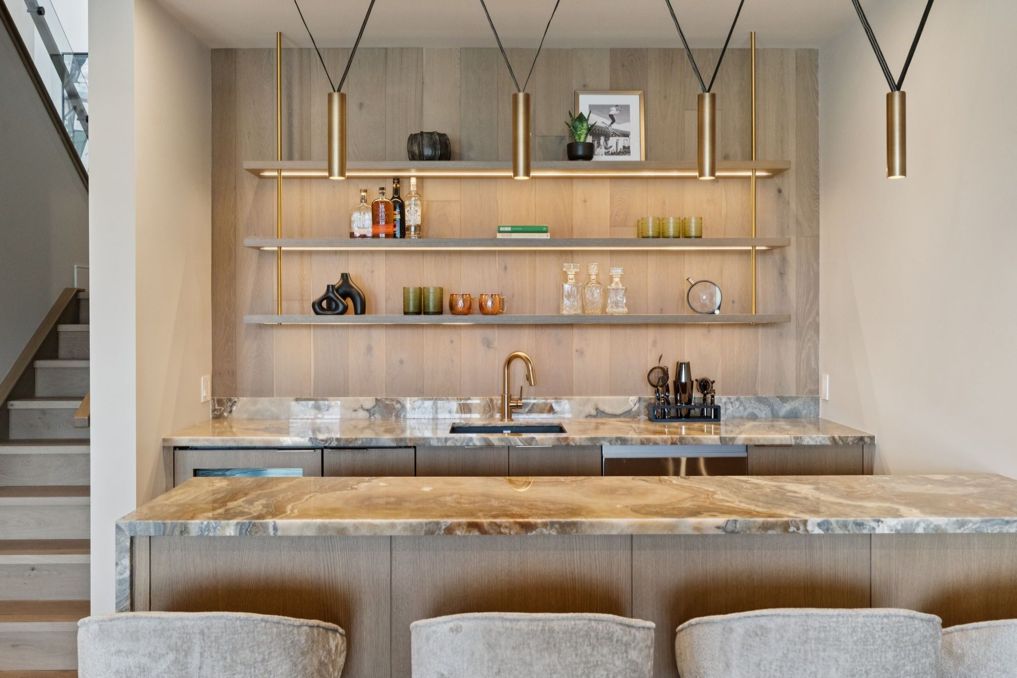 Una cocina moderna con encimeras de mármol, estantes de madera e iluminación colgante.