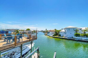 A marina with docked boats, a wooden deck with chairs, and a white building with a balcony. - Durango 121 pet friendly, private dock (Destin)