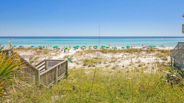 A beach with a wooden walkway leading to the sand, umbrellas, and a clear blue sky. - Private Beach Access, Sleeps 6, Pool & More! (Miramar Beach)