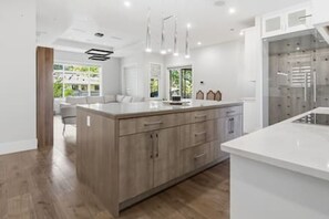 A modern kitchen with a central island, wooden cabinets, and pendant lighting. - Luxury 5-Bed Home, Sleeps 10, Quiet North Delta (Delta)
