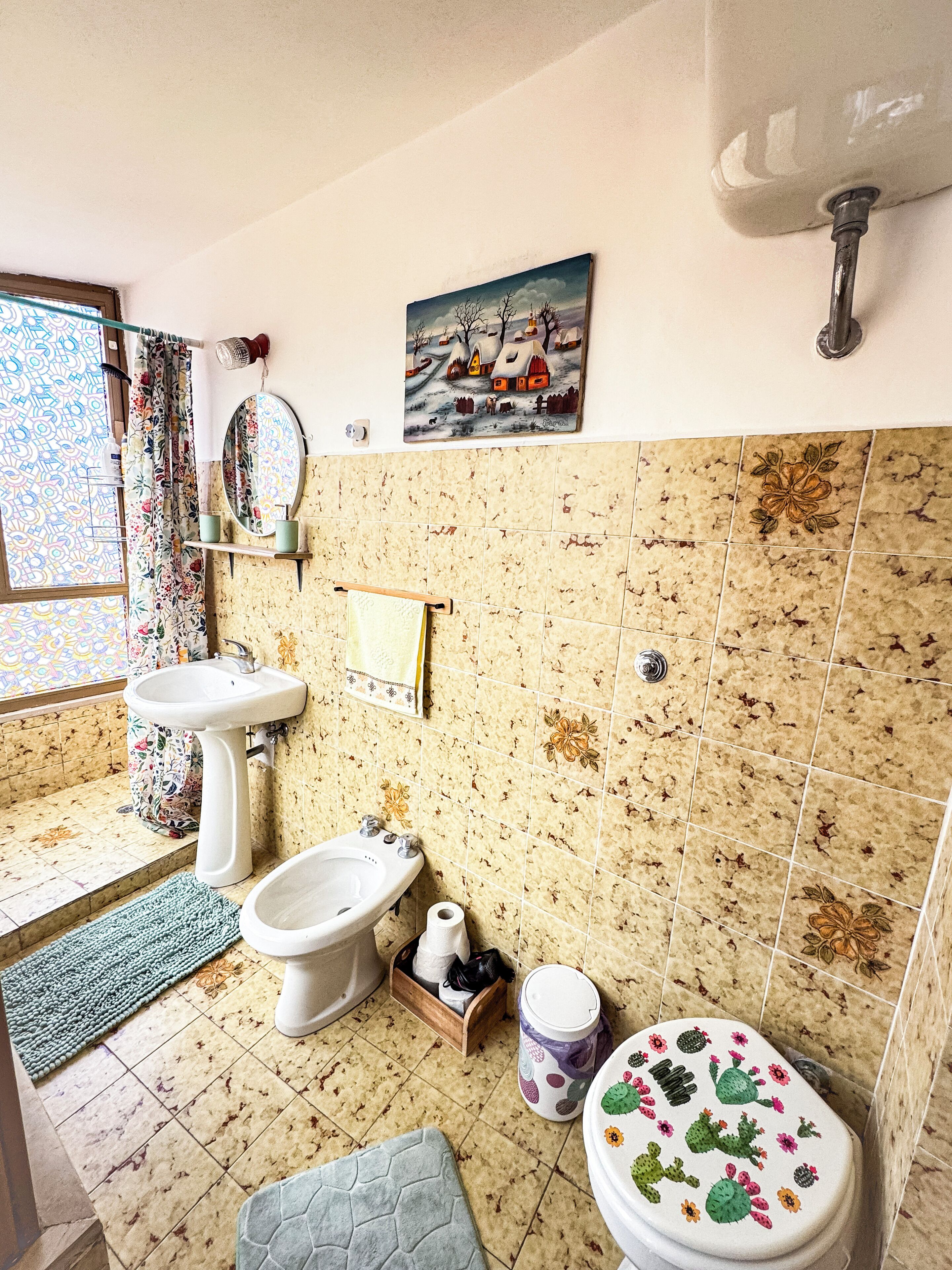 A bathroom with a sink, bidet, toilet, and decorative tiles.