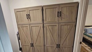 Ein Zimmer mit Schrank, Bett und einer Tür zu einem weiteren Raum.