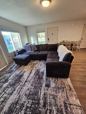 A living room with a sectional sofa, a coffee table, and a patterned rug.