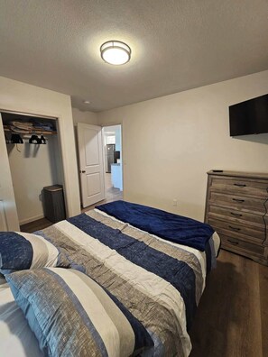 Ein Schlafzimmer mit Bett, Kommode, Fernseher und Schrank.
