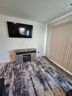 A room with a mounted TV, a wooden entertainment unit, and a patterned carpet.