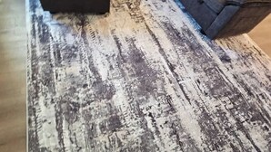 Ein Zimmer mit einer großen Eckcouch, einem gemusterten Teppich und einem geometrischen Fußbodenmuster.