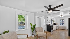 A modern kitchen with white cabinets, a black island, and a ceiling fan.