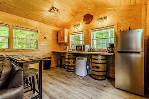 A wooden cabin interior with a kitchen, bar area, and seating. - 10 Minutes from downtown Sevierville. Firefly Cottage (Sevierville)