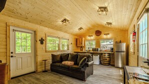 L’intérieur d’une cabane est doté d’un plafond en bois, d’un coin cuisine, d’un canapé et d’une porte avec des fenêtres.
