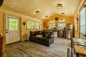 A cabin interior with a wooden ceiling, a kitchen area, a sofa, and a door with windows. - 10 Minutes from downtown Sevierville. Firefly Cottage (Sevierville)